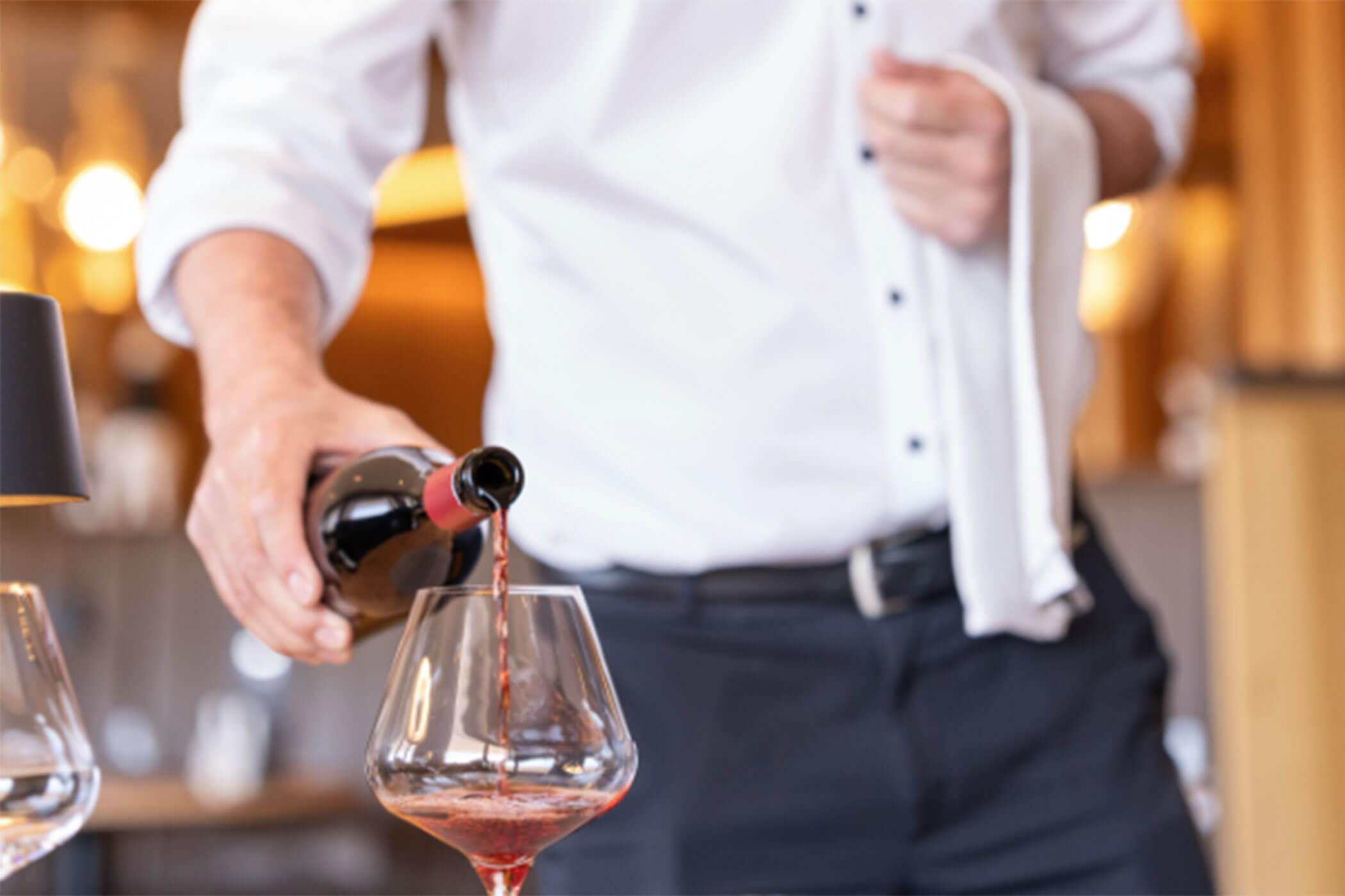 Ein Kellner schenkt Rotwein in ein Glas ein. - Hotel DAS ROYAL