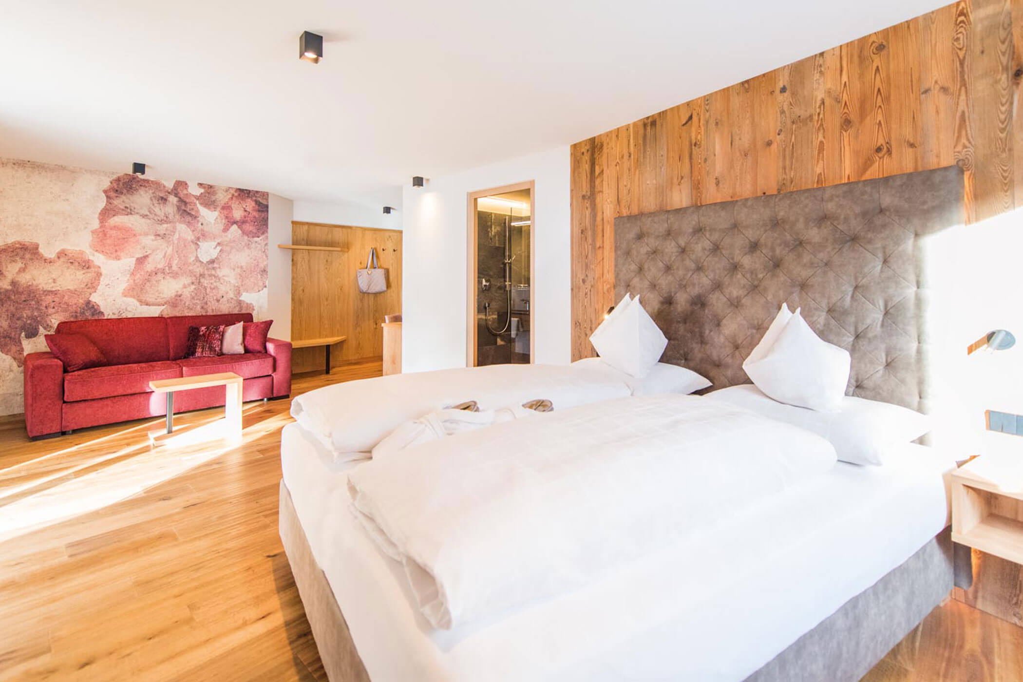 Hotelzimmer mit einem Bett, einem roten Sofa und einem eigenen Bad. - Hotel DAS ROYAL