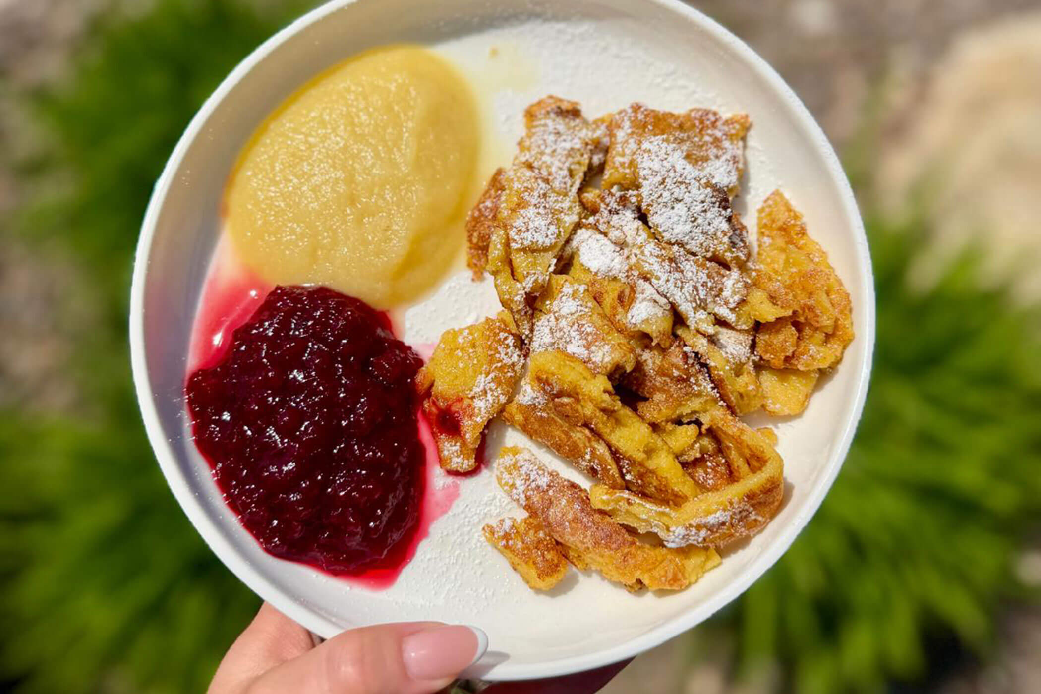 Kaiserschmarrn mit Puderzucker, Apfelmus und Preiselbeerkonfitüre auf einem weißen Teller. - Hotel DAS ROYAL